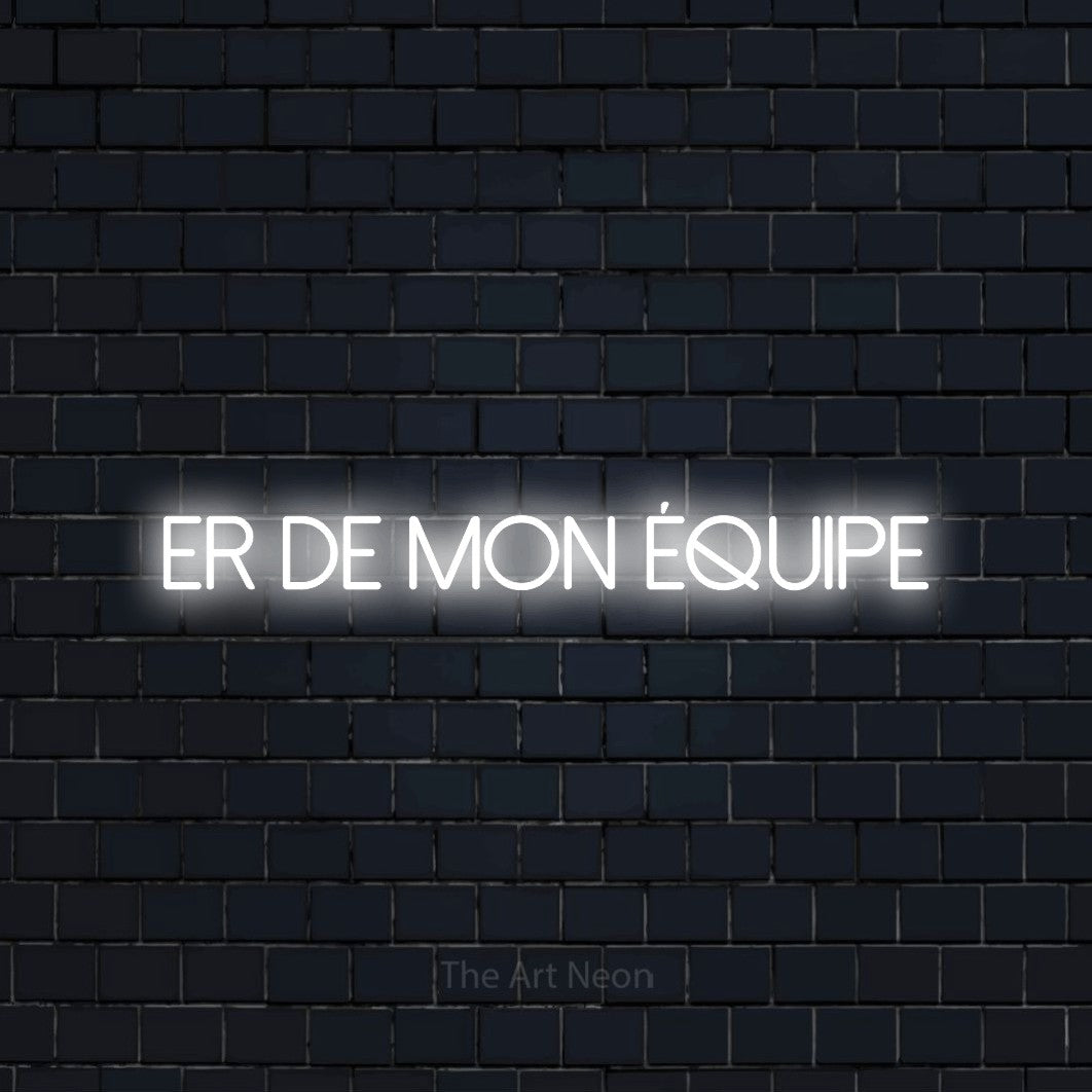 “Fier de mon équipe” LED neon sign in cool white, with thin sans-serif lettering, shown against a dark navy brick wall.
