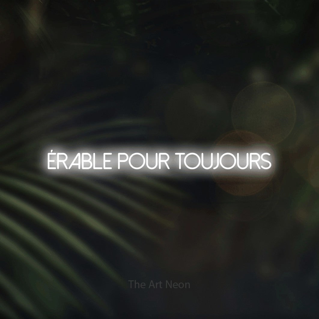 “Érable pour toujours” LED neon sign in cool white, with thin sans-serif lettering, shown against a blurred palm and bokeh-light backdrop.
