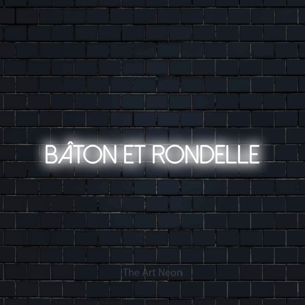 “Bâton et rondelle” LED neon sign in cool white, with thin sans-serif lettering, shown against a dark navy brick wall.