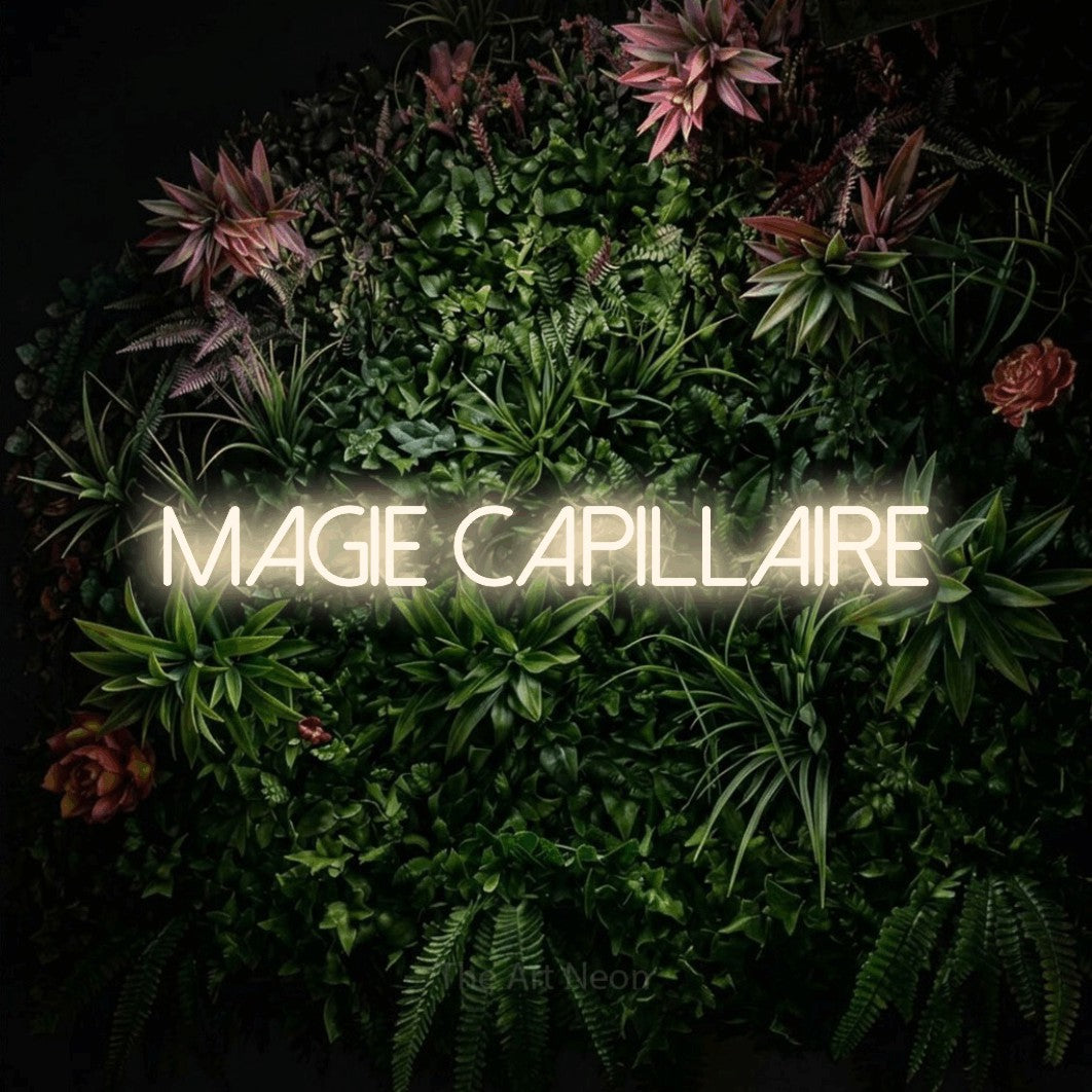 “Magie capillaire” LED neon sign in warm white, with thin sans-serif lettering, shown against a flowering plant wall.