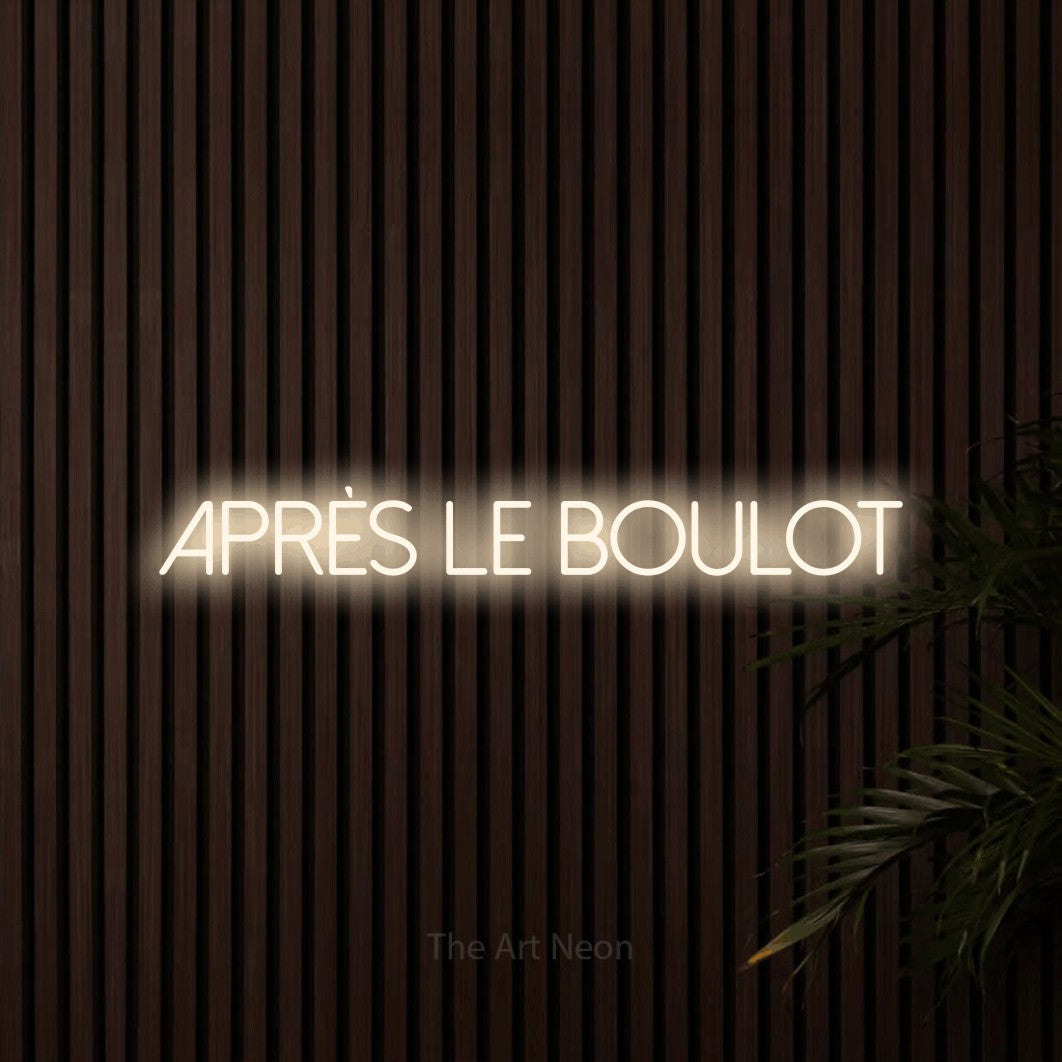 Décoration murale en néon LED « Après le boulot » en blanc chaud, en lettres fines sans empattement, installée sur un mur de lattes en bois foncé, pour un bar ou un pub.