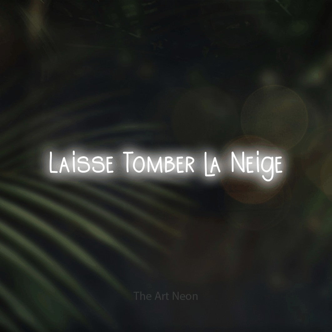 “Laisse tomber la neige” LED neon sign in cool white, with narrow hand-drawn lettering, shown against a blurred palm and bokeh-light backdrop.