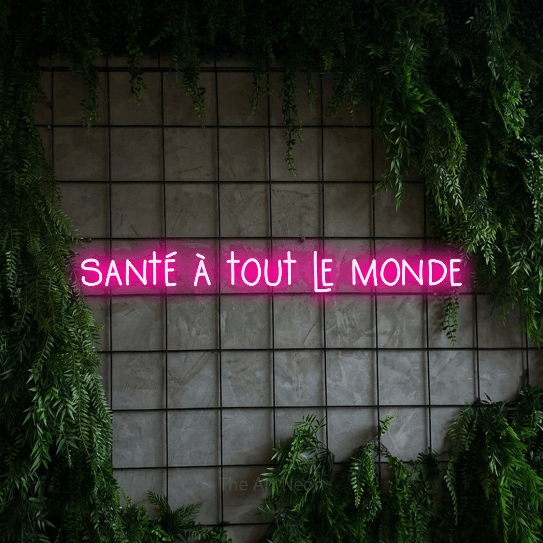 Composition en néon LED « Santé à tout le monde » en rose vif, en lettres étroites dessinées à la main, mise en valeur sur une grille de béton couverte de lierre, pour un bar ou un pub.