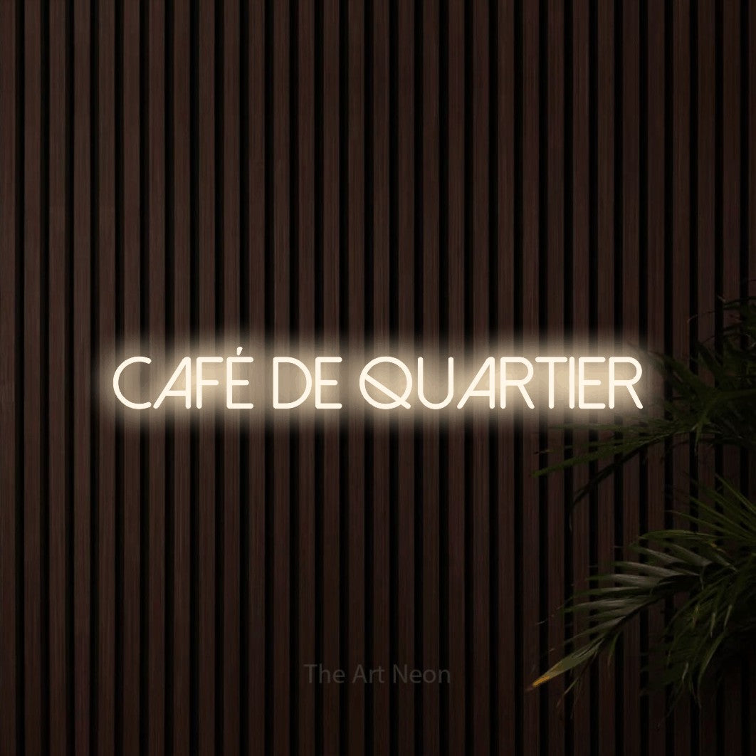 “Café de quartier” LED neon sign in warm white, with thin sans-serif lettering, shown against dark wooden wall slats.