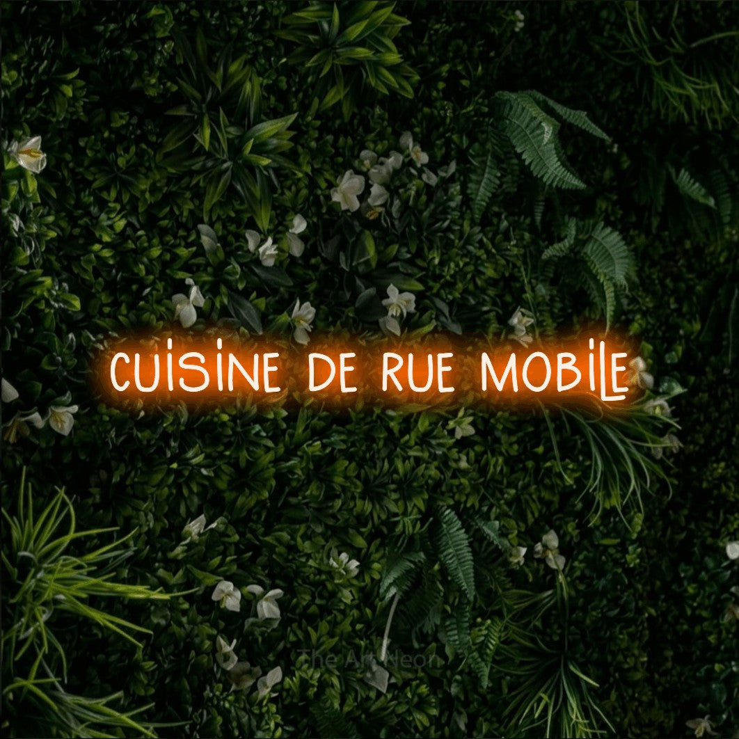 “Cuisine de rue mobile” LED neon sign in orange, with narrow hand-drawn lettering, shown against a dense green plant wall.