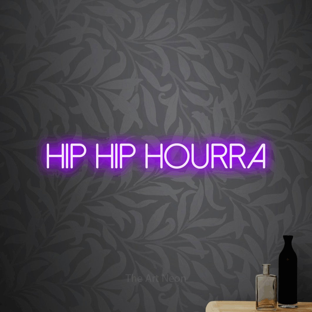 Décoration murale en néon LED « Hip hip hourra » en violet, en lettres fines sans empattement, installée sur un papier peint botanique gris, pour une fête.