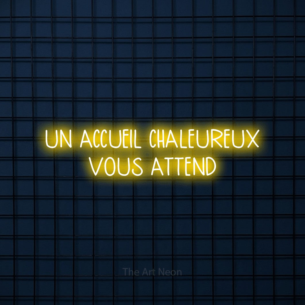 “Un accueil chaleureux vous attend” LED neon sign in yellow, with narrow hand-drawn lettering across 2 lines, shown against a dark blue grid.