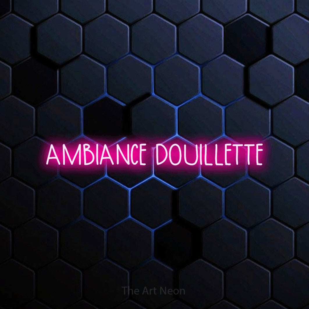“Ambiance douillette” LED neon sign in hot pink, with narrow hand-drawn lettering, shown against a dark blue honeycomb pattern.