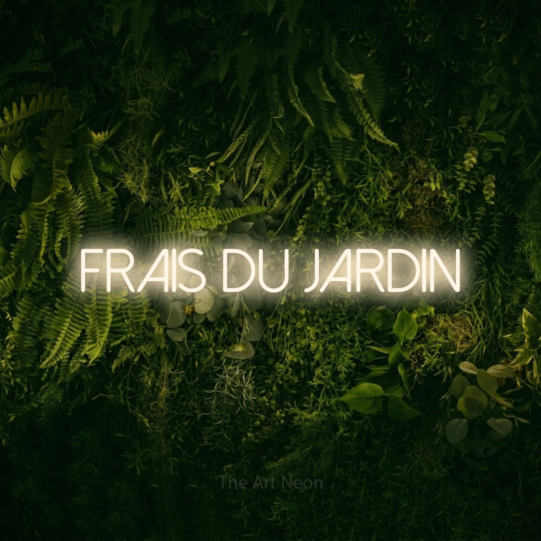 “Frais du jardin” LED neon sign in warm white, with thin sans-serif lettering, shown against a dark moss and forest backdrop.