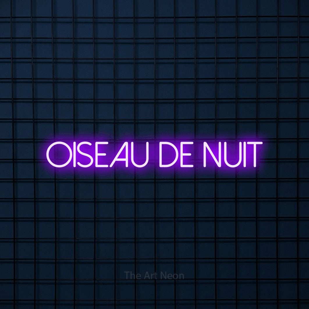 “Oiseau de nuit” LED neon sign in purple, with thin sans-serif lettering, shown against a dark blue grid.