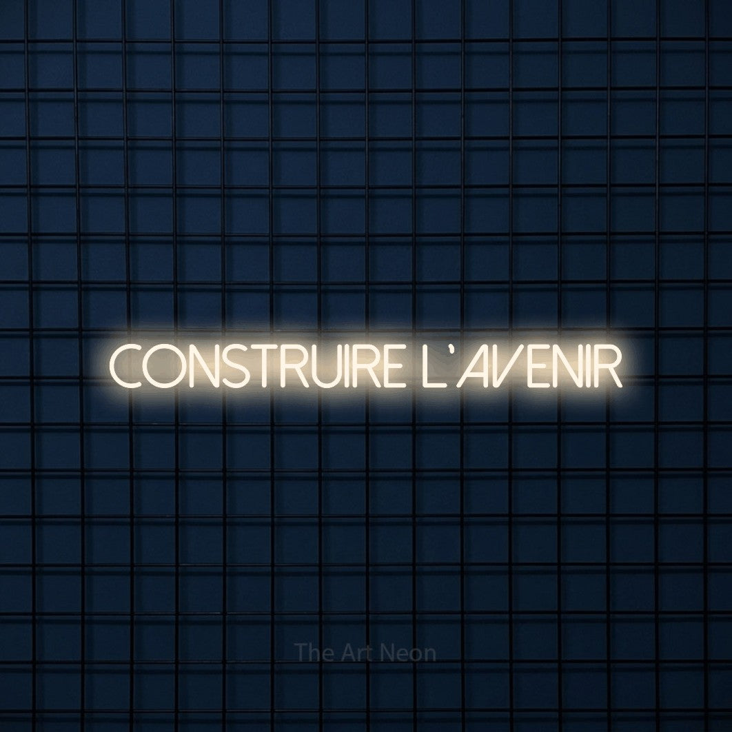 “Construire l'avenir” LED neon sign in warm white, with thin sans-serif lettering, shown against a dark blue grid.