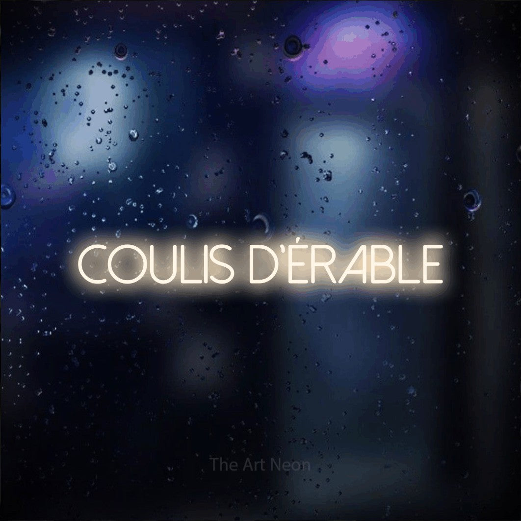 “Coulis d'érable” LED neon sign in warm white, with thin sans-serif lettering, shown against glass with blue and purple reflections.