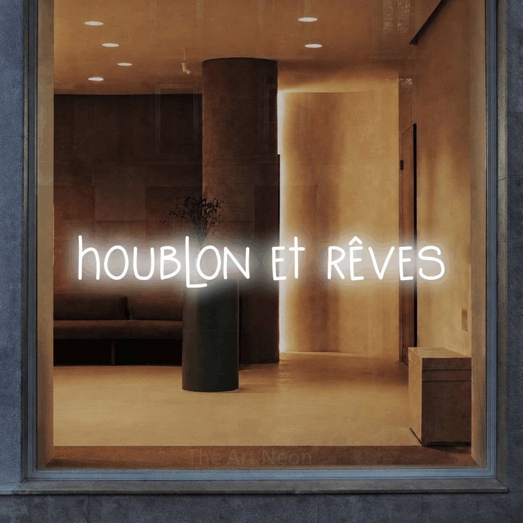 “Houblon et rêves” LED neon sign in cool white, with narrow hand-drawn lettering, shown against a warm-toned interior.