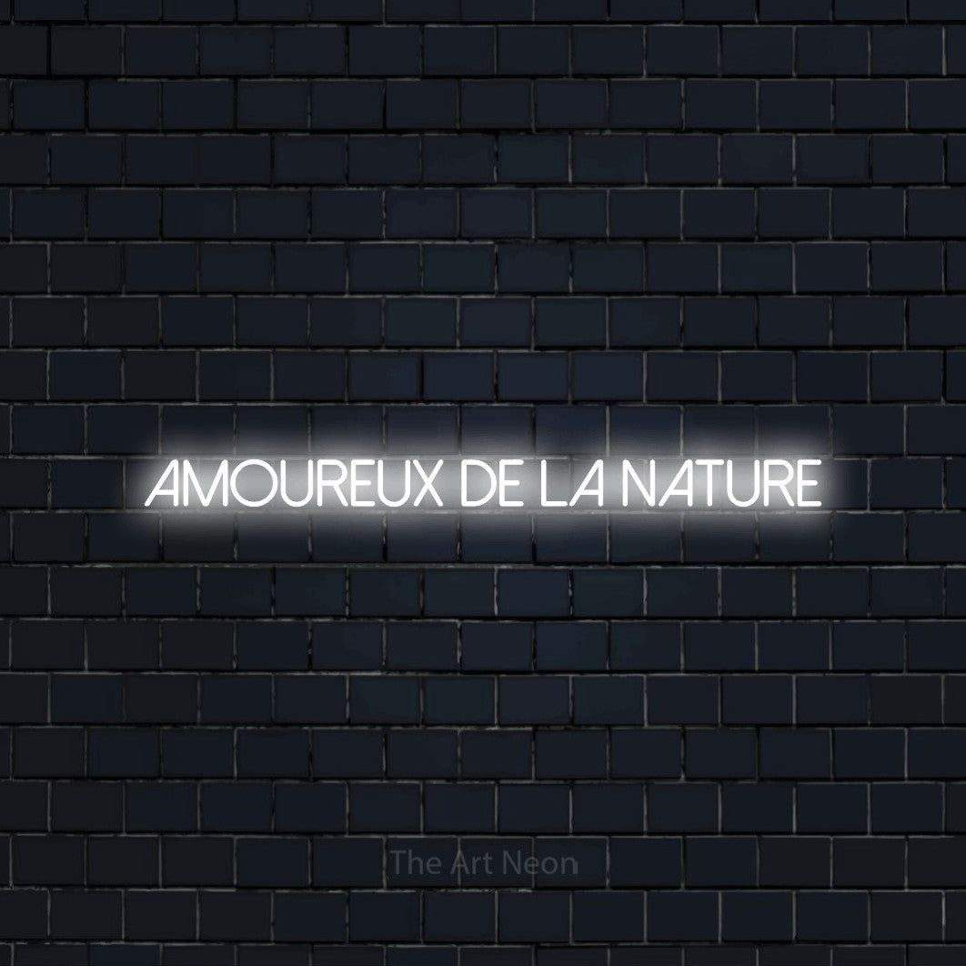 “Amoureux de la nature” LED neon sign in cool white, with thin sans-serif lettering, shown against a dark navy brick wall.