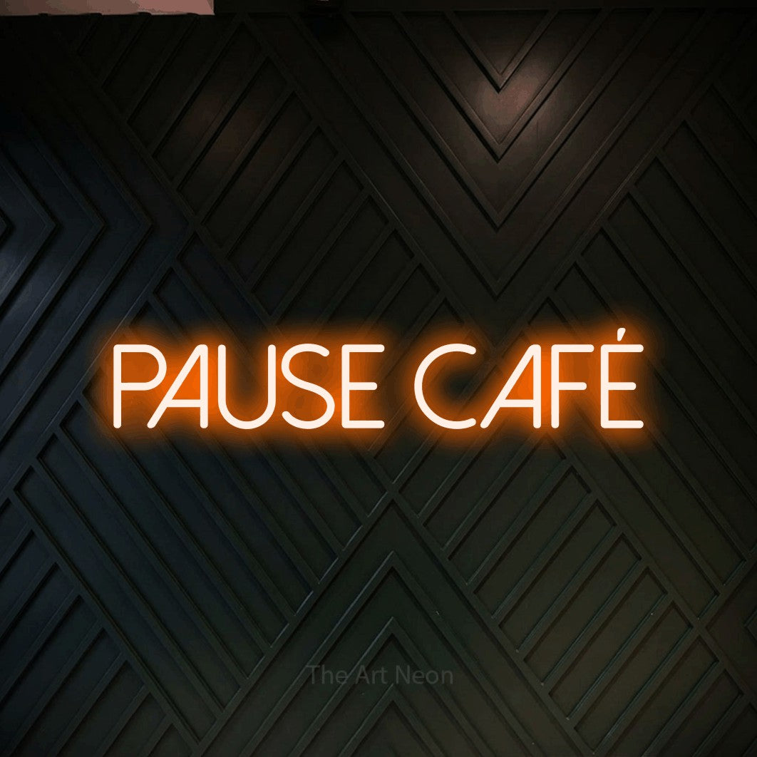 “Pause café” LED neon sign in orange, with thin sans-serif lettering, shown against a black chevron-patterned wood wall.