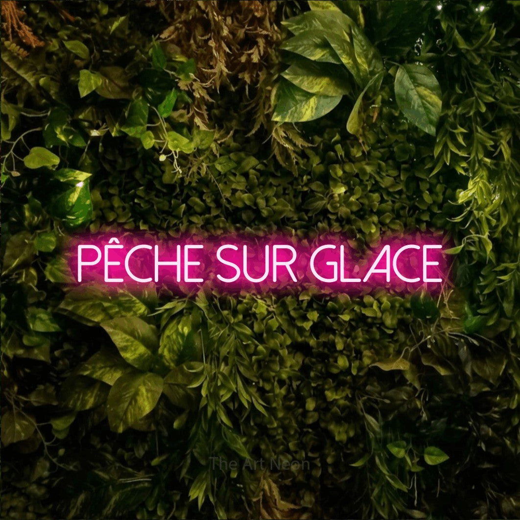 “Pêche sur glace” LED neon sign in hot pink, with thin sans-serif lettering, shown against bright green and yellow foliage.