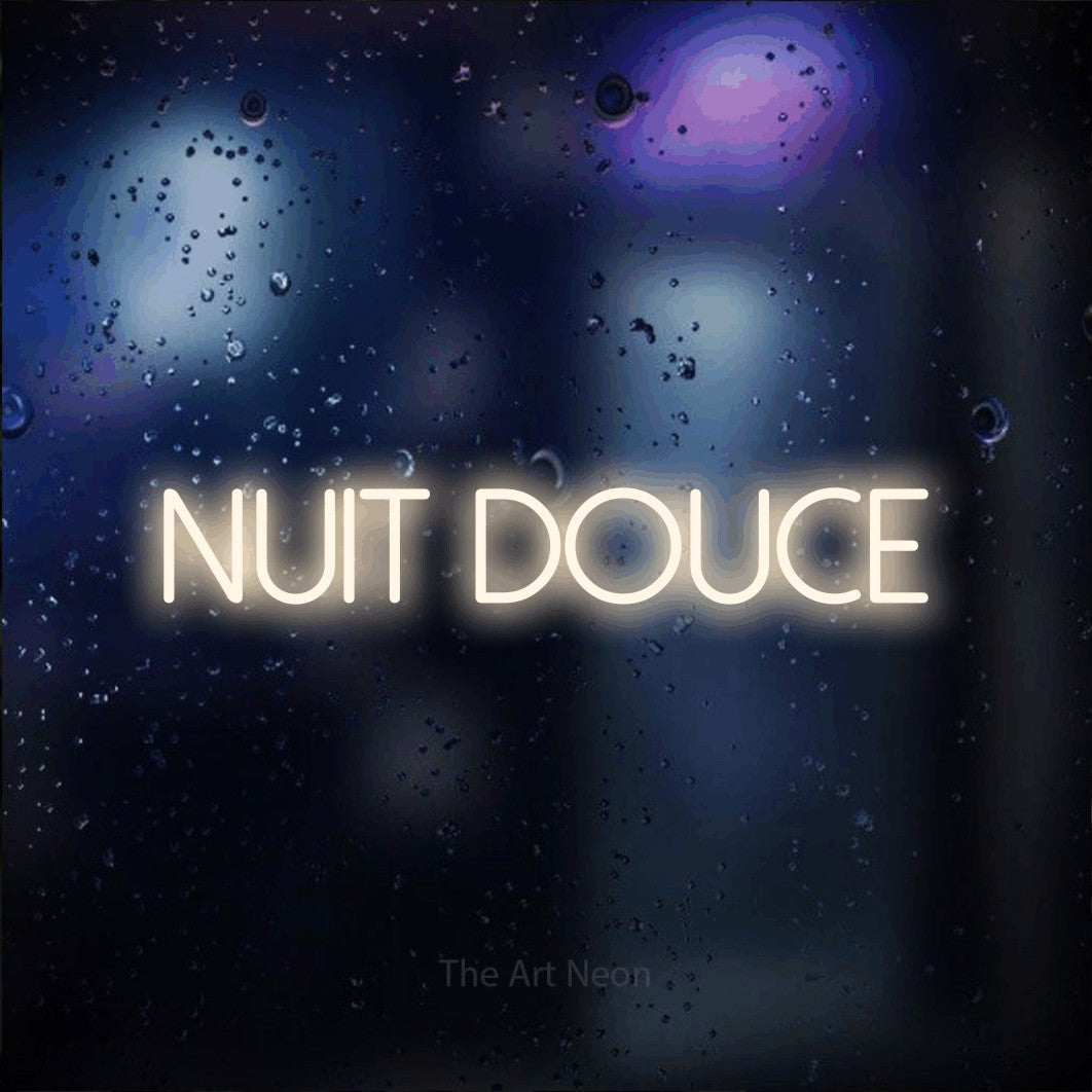 “Nuit douce” LED neon sign in warm white, with thin sans-serif lettering, shown against glass with blue and purple reflections.