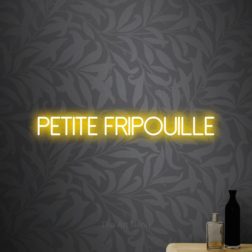 “Petite fripouille” LED neon sign in yellow, with thin sans-serif lettering, shown against grey botanical wallpaper.