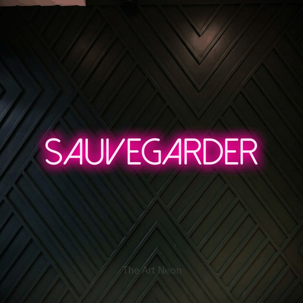 “Sauvegarder” LED neon sign in hot pink, with thin sans-serif lettering, shown against a black chevron-patterned wood wall.