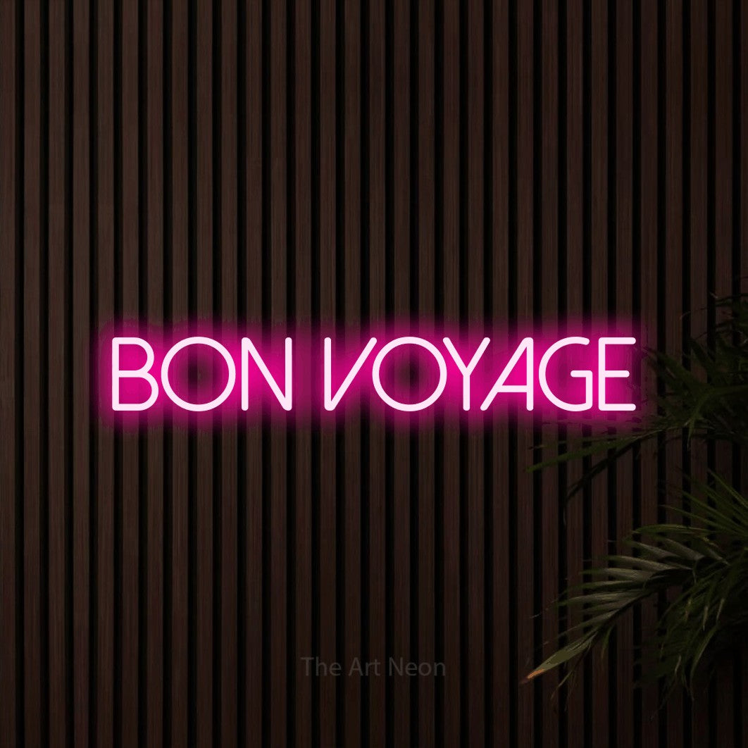 “Bon voyage” LED neon sign in hot pink, with thin sans-serif lettering, shown against dark wooden wall slats.