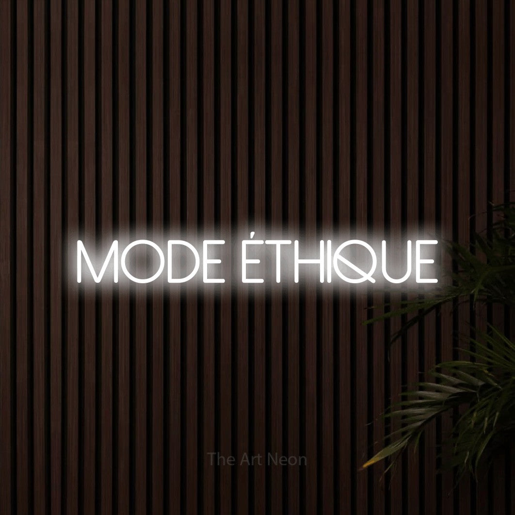 “Mode éthique” LED neon sign in cool white, with thin sans-serif lettering, shown against dark wooden wall slats.