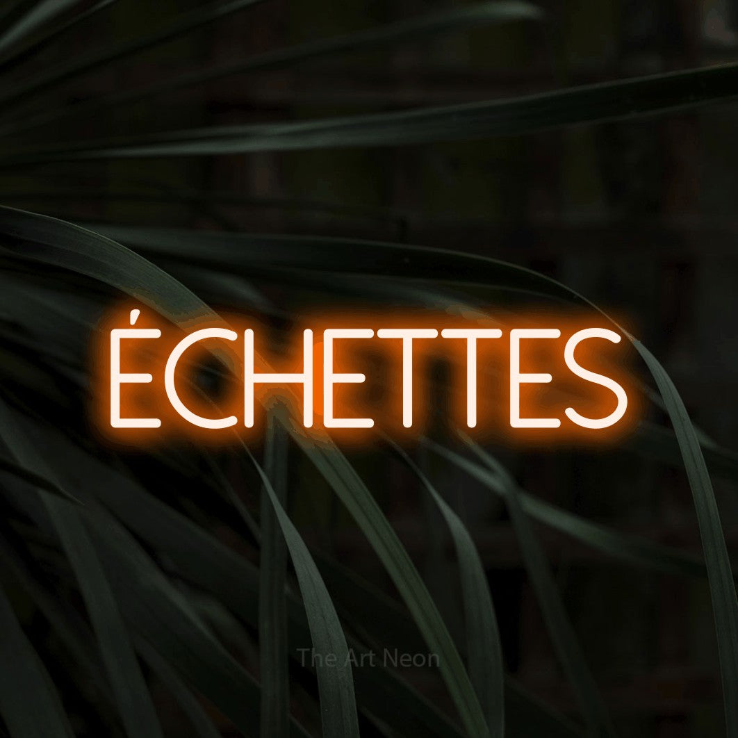 “Fléchettes” LED neon sign in orange, with thin sans-serif lettering, shown against a close-up of dark foliage.