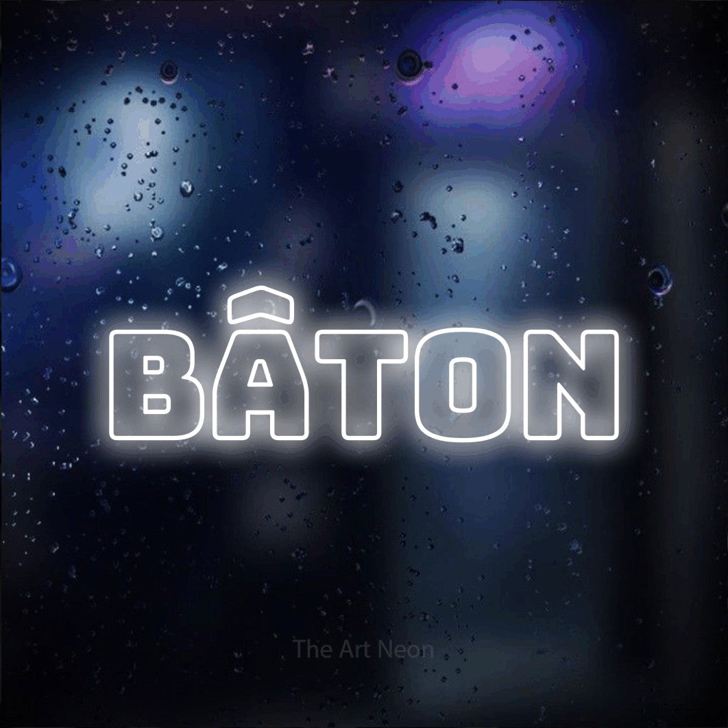 “Bâton” LED neon sign in cool white, with bold outline lettering, shown against glass with blue and purple reflections.