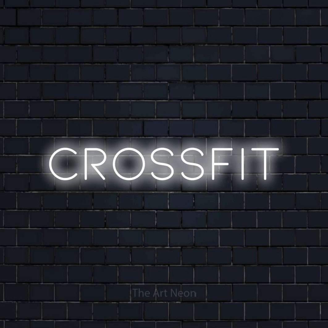 Décoration murale en néon LED « CrossFit » en blanc froid, en lettres fines et espacées, installée sur un mur de briques bleu marine foncé, pour un espace d’entraînement.