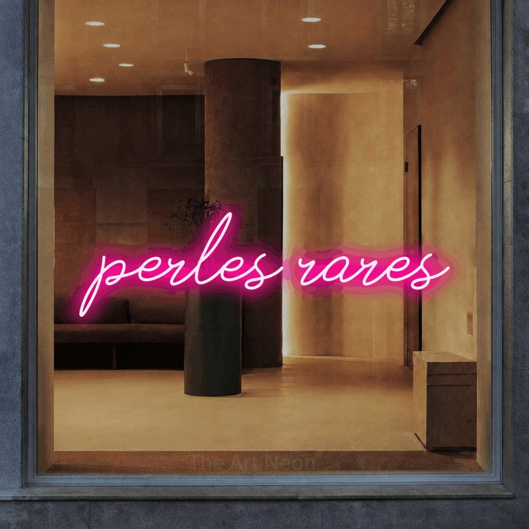 “Perles rares” LED neon sign in hot pink, with cursive lettering, shown against a warm-toned interior.