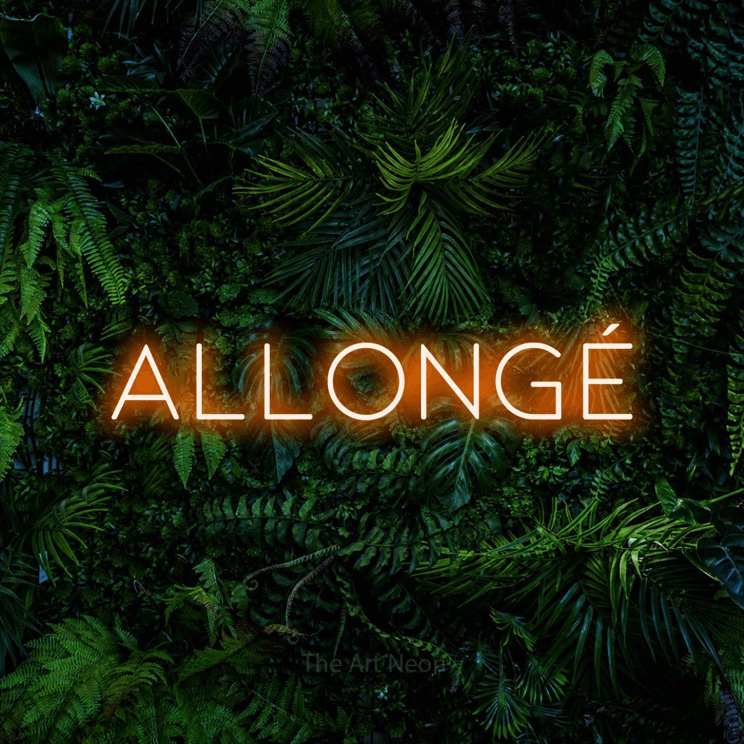 Aperçu d’une enseigne néon LED « Allongé » en orange, en lettres fines et espacées, photographiée devant un feuillage tropical dense, pour un café.