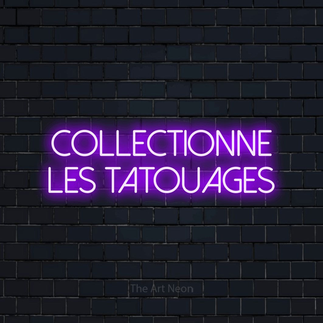 “Collectionne les tatouages” LED neon sign in purple, with thin sans-serif lettering across 2 lines, shown against a dark navy brick wall.