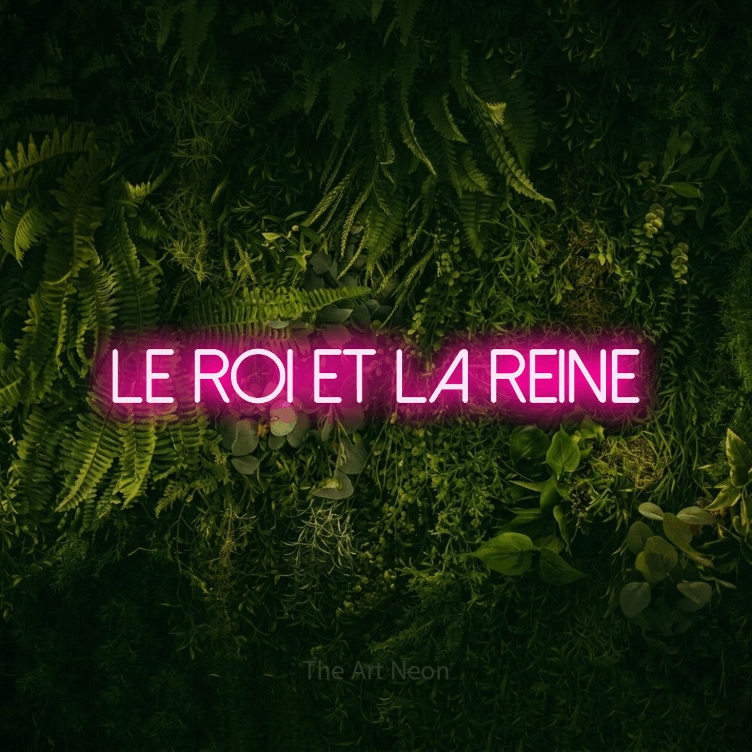 “Le roi et la reine” LED neon sign in hot pink, with thin sans-serif lettering, shown against a dark moss and forest backdrop.