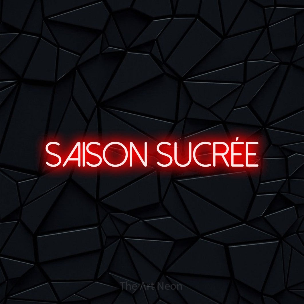 “Saison sucrée” LED neon sign in red, with thin sans-serif lettering, shown against a black polygonal surface.