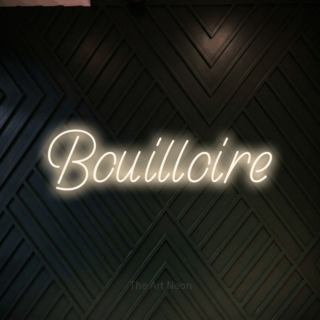 “Bouilloire” LED neon sign in warm white, with slanted handwritten lettering, shown against a black chevron-patterned wood wall.