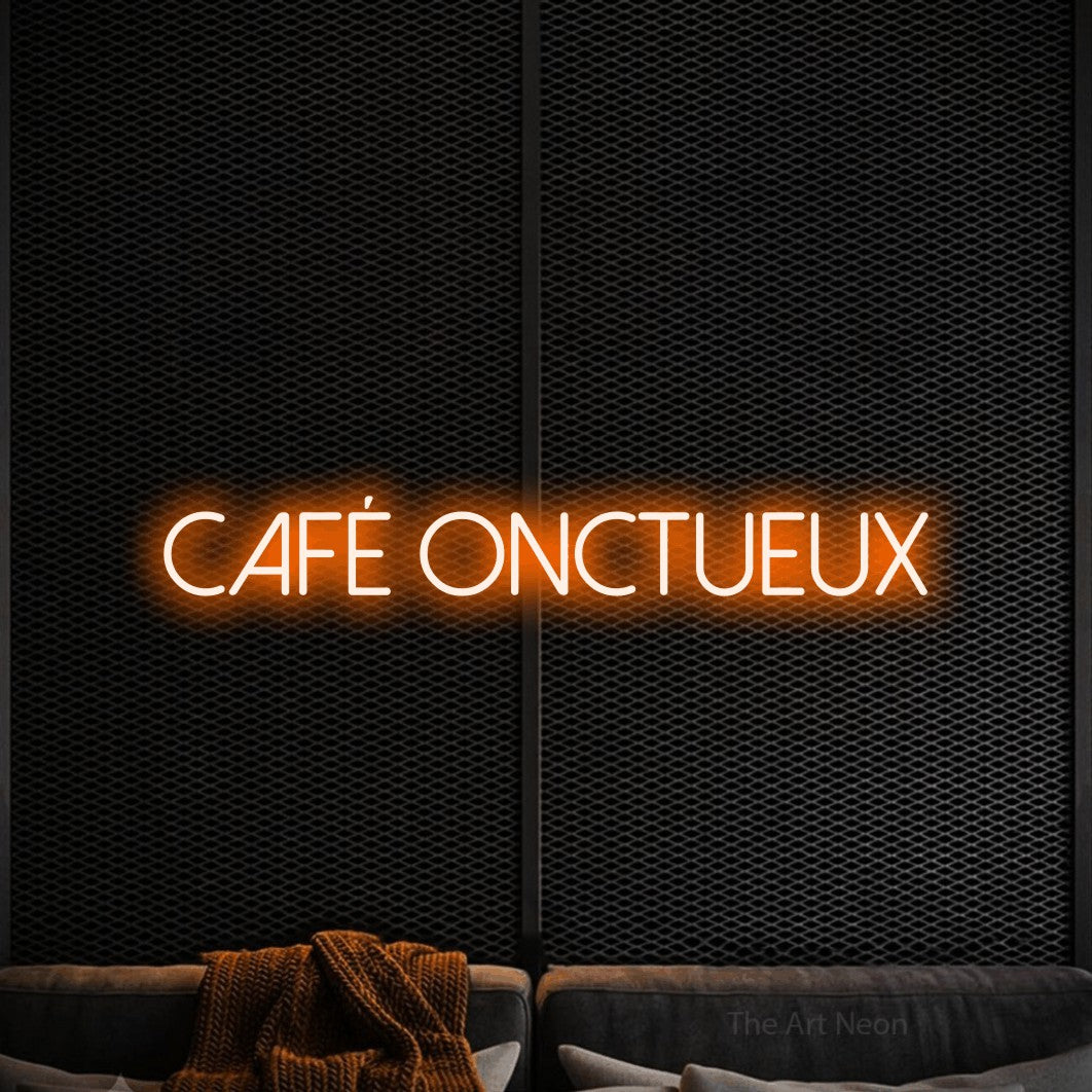 “Café onctueux” LED neon sign in orange, with thin sans-serif lettering, shown against a modern dark-toned seating area.