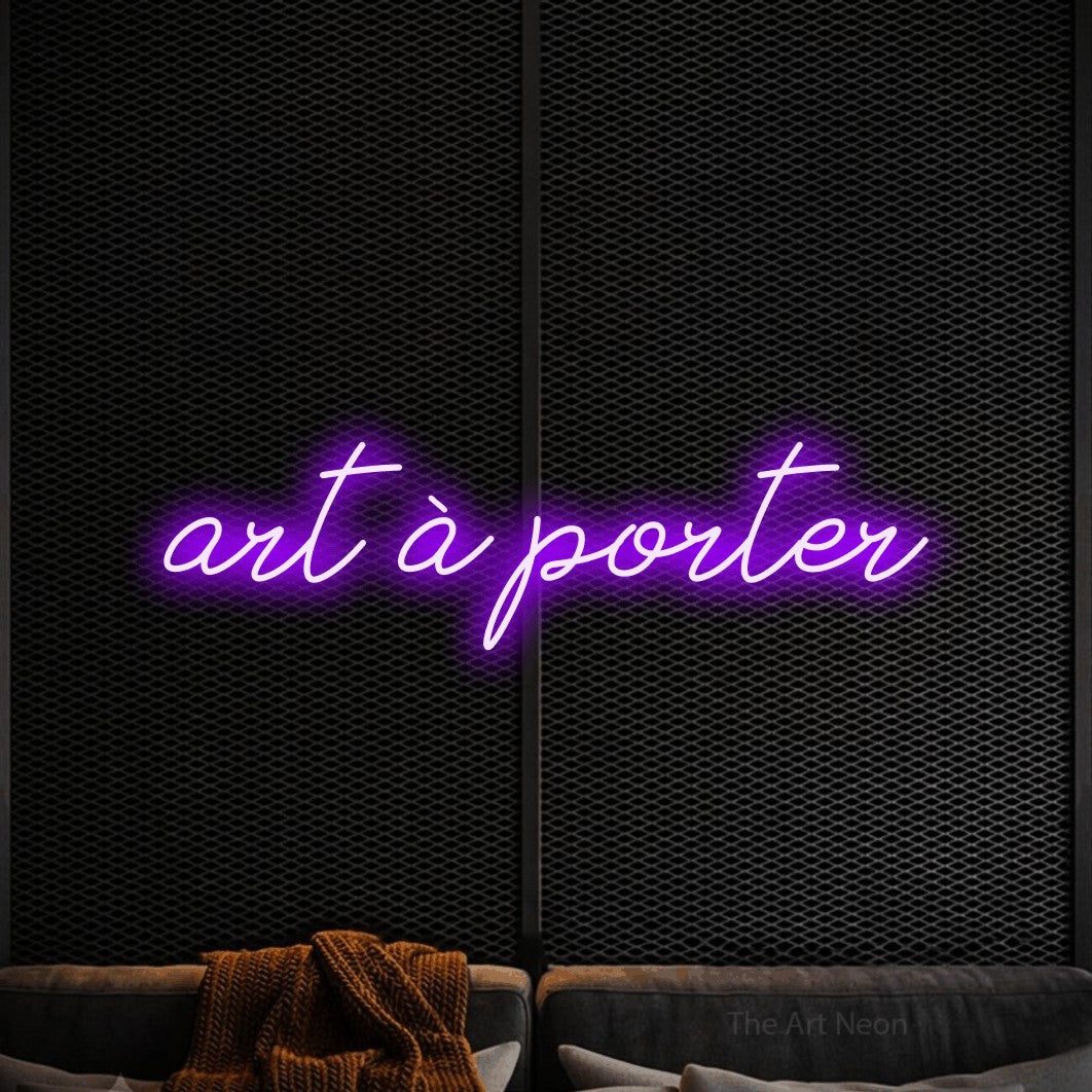 “Art à porter” LED neon sign in purple, with cursive lettering, shown against a modern dark-toned seating area.