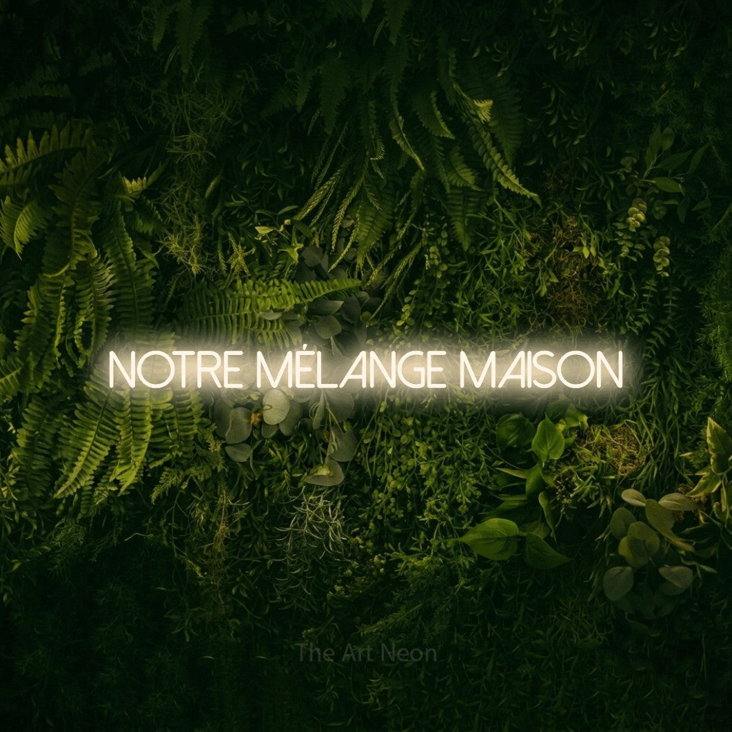 “Notre mélange maison” LED neon sign in warm white, with thin sans-serif lettering, shown against a dark moss and forest backdrop.