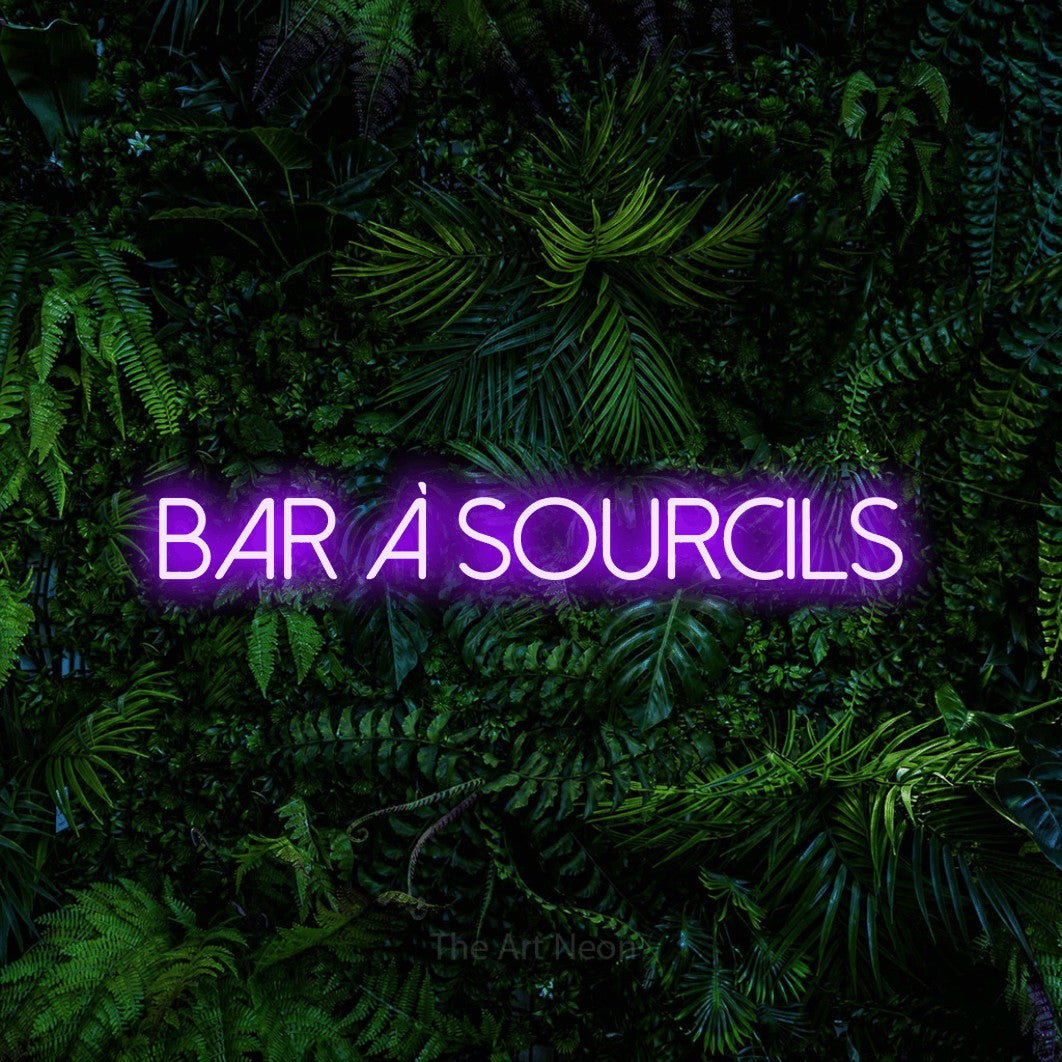 Composition en néon LED « Bar à sourcils » en violet, en lettres fines sans empattement, mise en valeur devant un feuillage tropical dense, pour un salon de beauté.