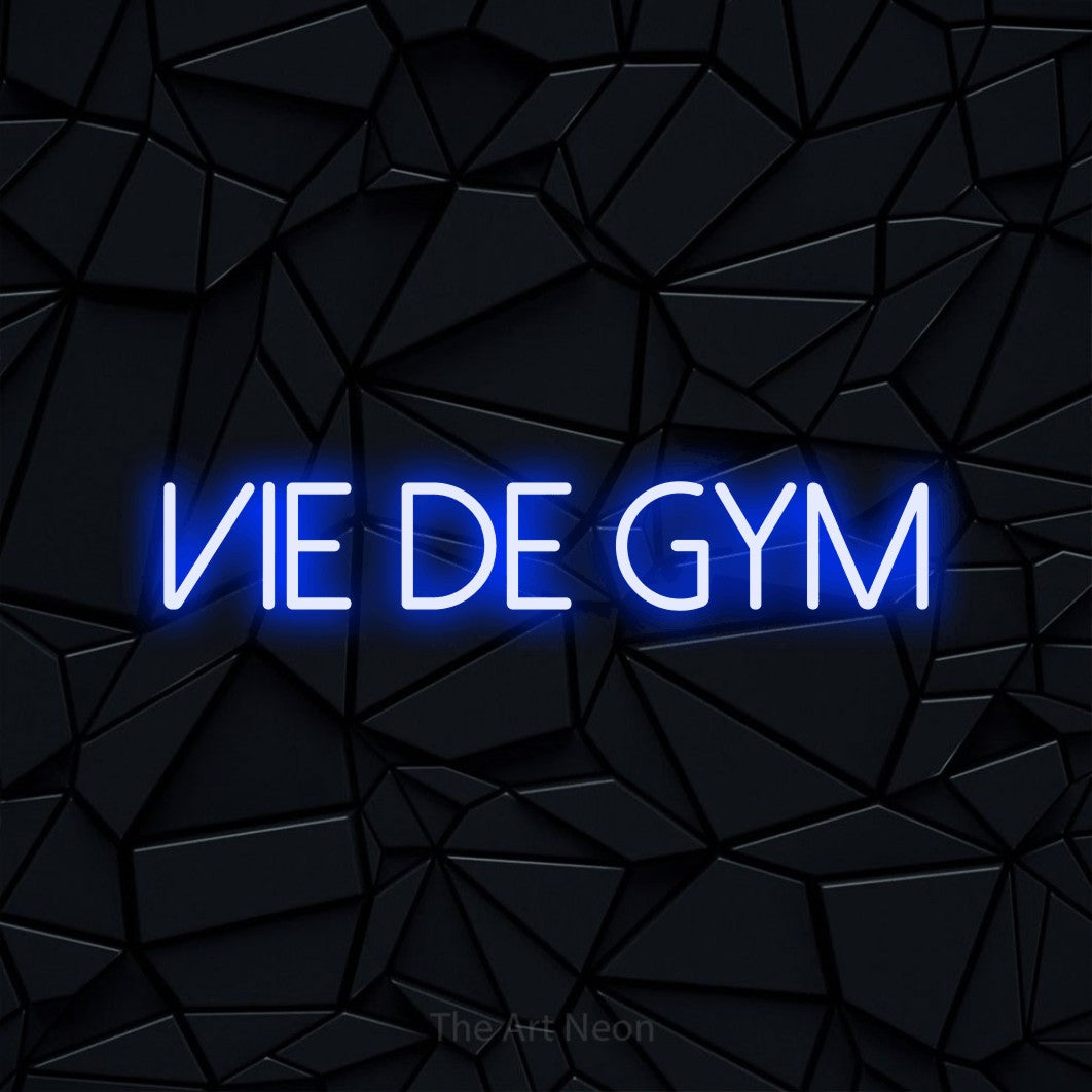 Aperçu d’une enseigne néon LED « Vie de gym » en bleu, en lettres fines sans empattement, photographiée sur une surface polygonale noire, pour un espace d’entraînement.