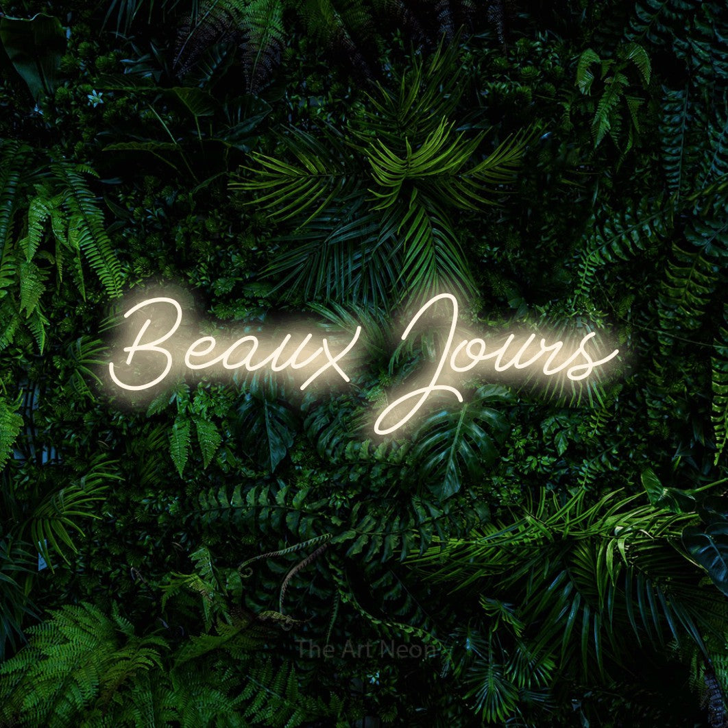 “Beaux jours” LED neon sign in warm white, with cursive lettering, shown against dense tropical foliage.