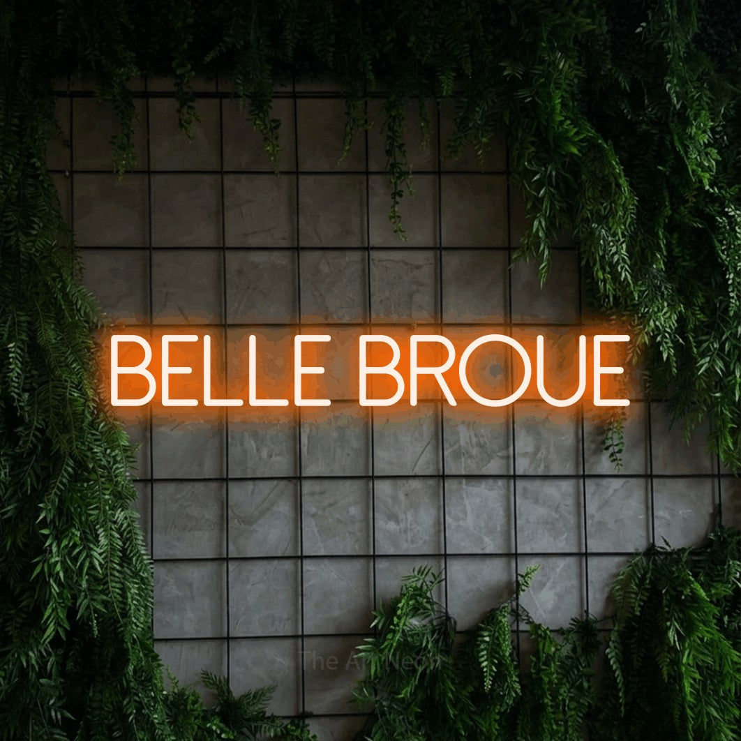 “Belle broue” LED neon sign in orange, with thin sans-serif lettering, shown against an ivy-covered concrete grid.