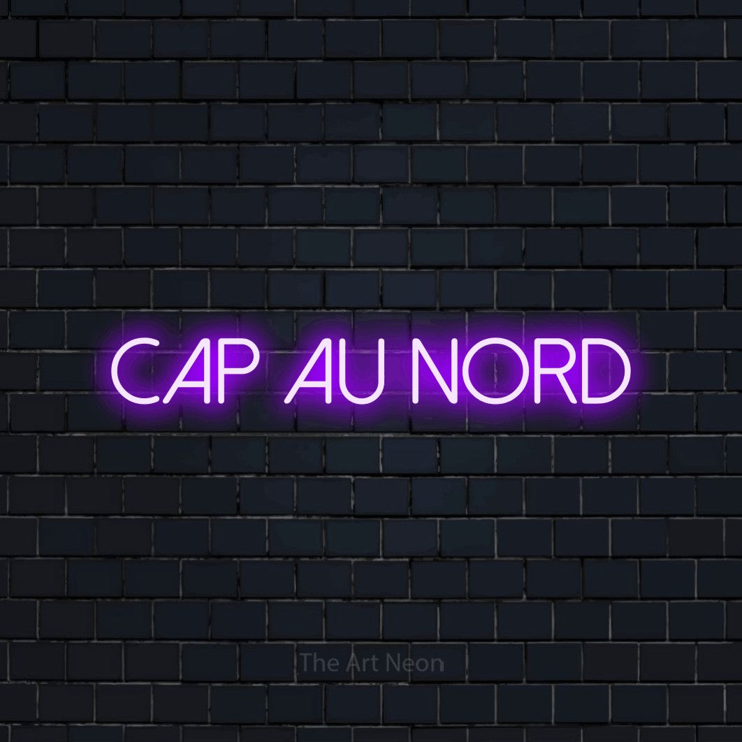 “Cap au nord” LED neon sign in purple, with thin sans-serif lettering, shown against a dark navy brick wall.