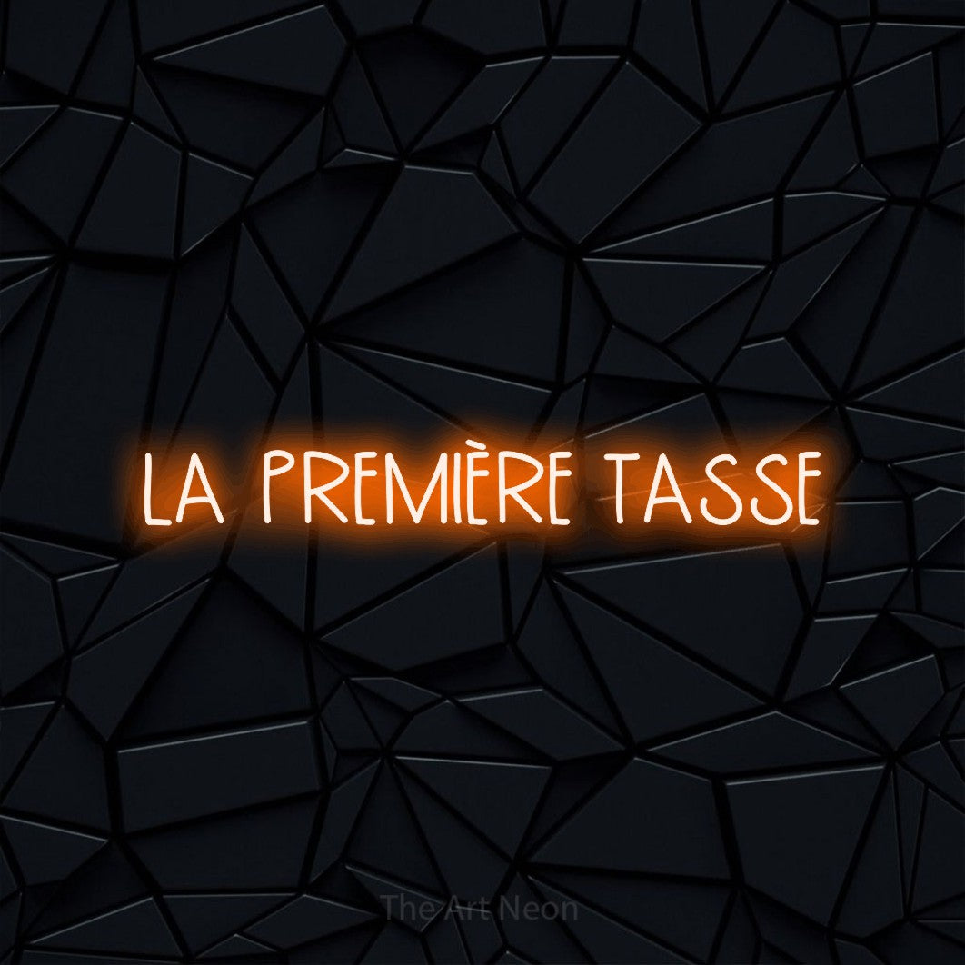 Aperçu d’une enseigne néon LED « La première tasse » en orange, en lettres étroites dessinées à la main, photographiée sur une surface polygonale noire, pour un café.