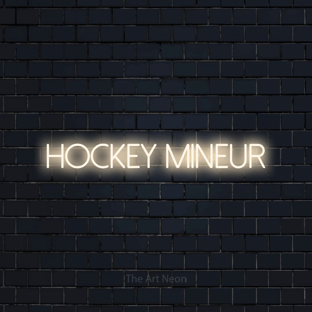 “Hockey mineur” LED neon sign in warm white, with thin sans-serif lettering, shown against a dark navy brick wall.