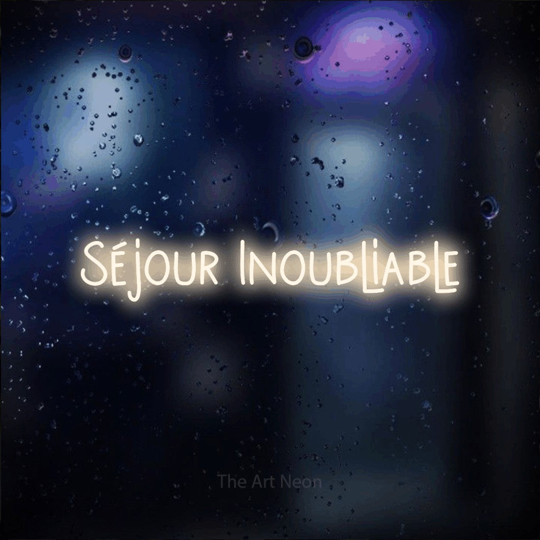 “Séjour inoubliable” LED neon sign in warm white, with narrow hand-drawn lettering, shown against glass with blue and purple reflections.