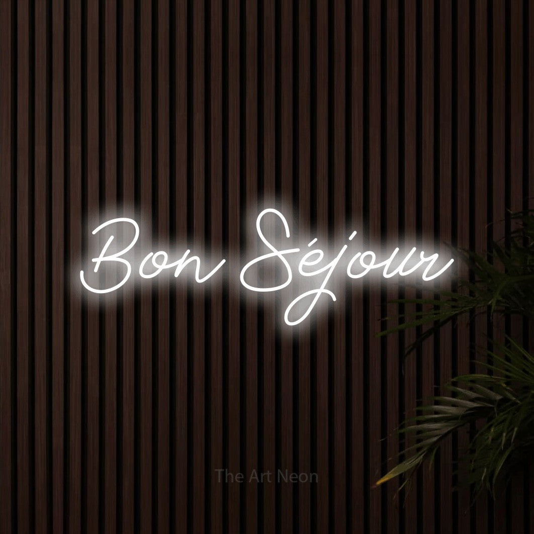 “Bon séjour” LED neon sign in cool white, with cursive lettering, shown against dark wooden wall slats.