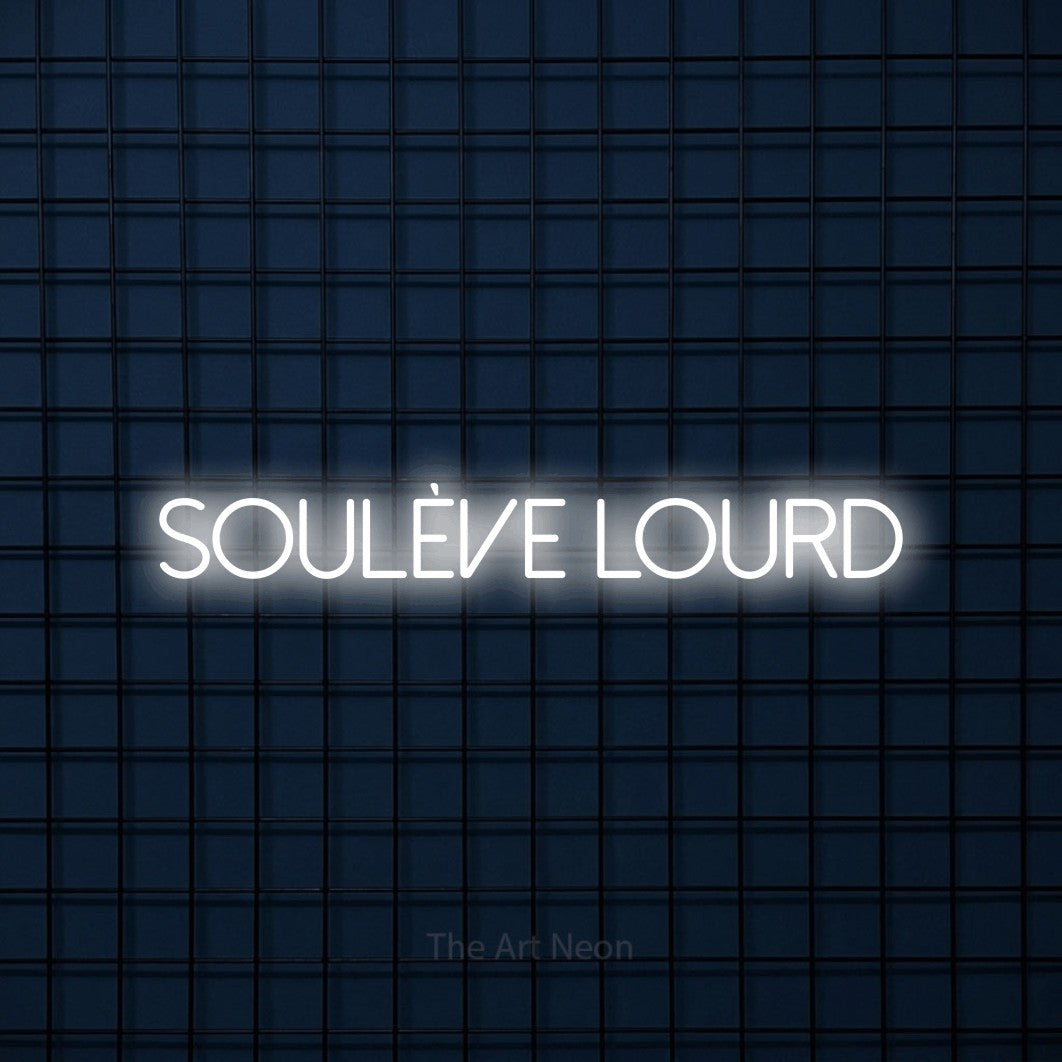“Soulève lourd” LED neon sign in cool white, with thin sans-serif lettering, shown against a dark blue grid.