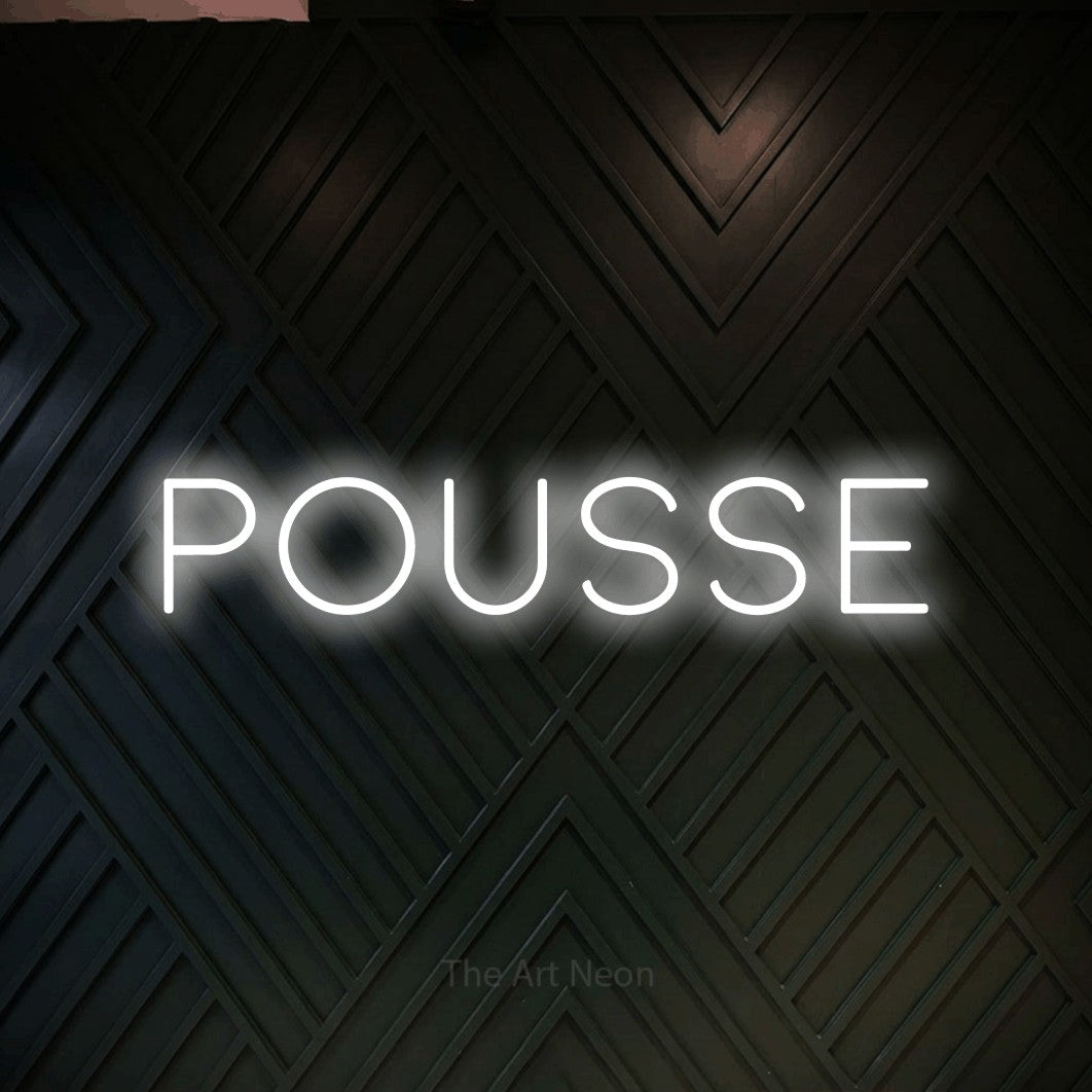 “Pousse” LED neon sign in cool white, with thin, widely spaced lettering, shown against a black chevron-patterned wood wall.