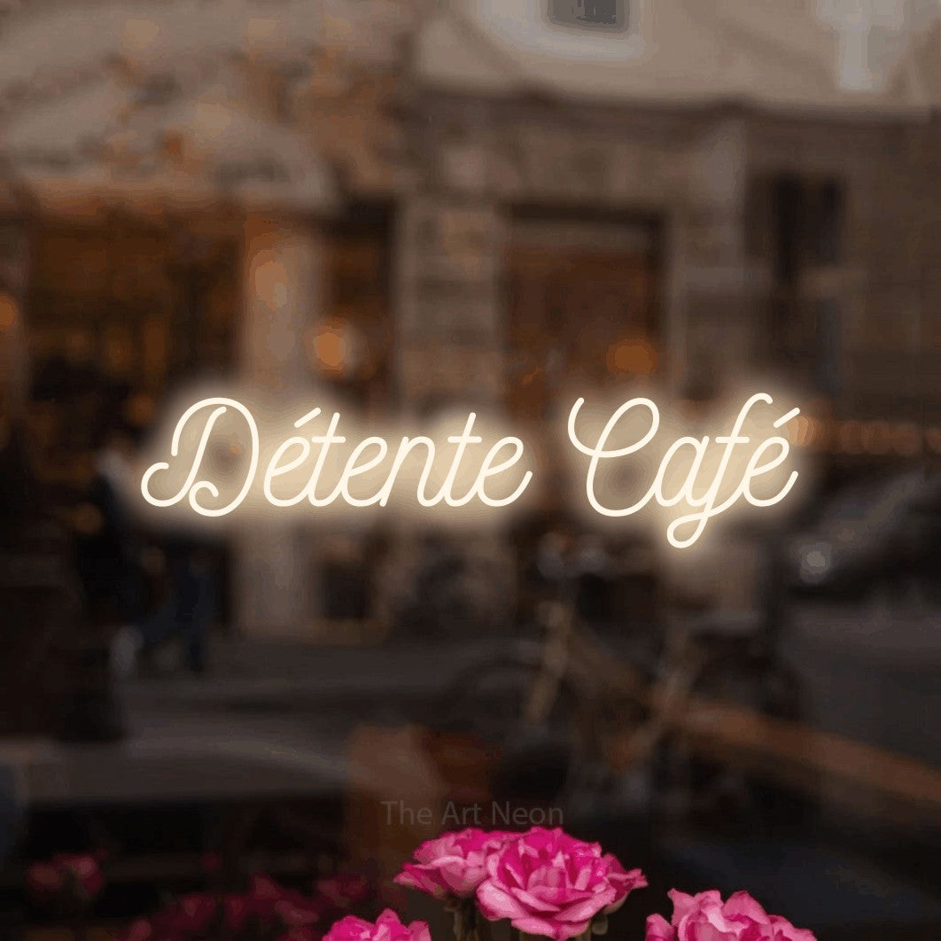 Enseigne néon LED « Détente café » en blanc chaud, en écriture cursive ornée, présentée dans un décor flou de café-bar, pour un café.