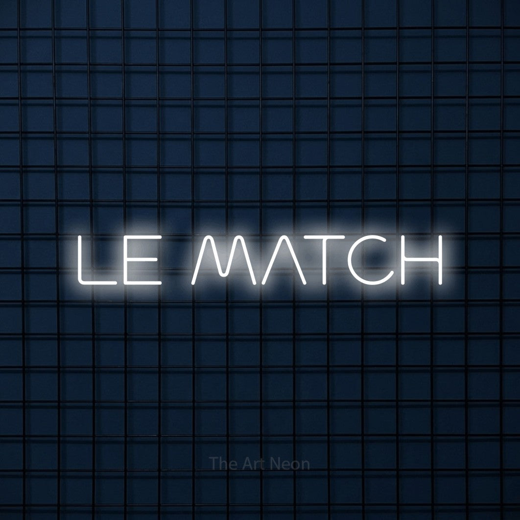 “Le match” LED neon sign in cool white, with stylised geometric lettering, shown against a dark blue grid.
